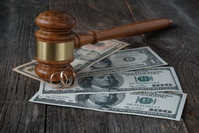 gavel on dollar bills with wedding rings