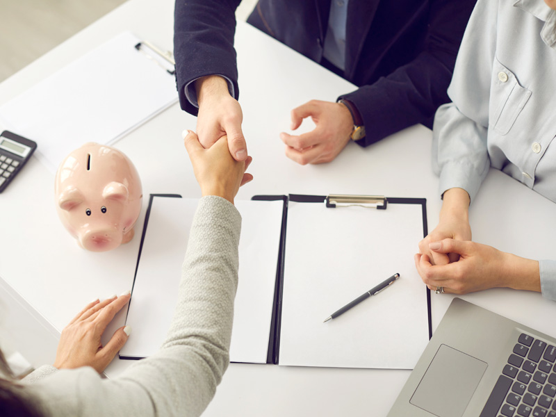 High angle of handshake over table with finance papers