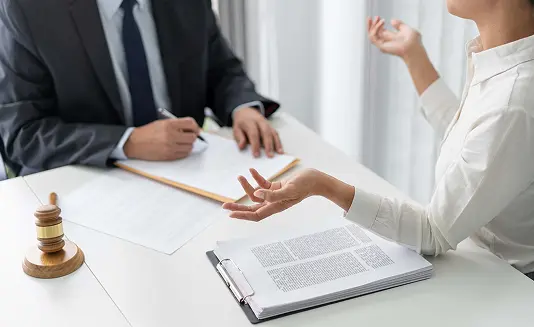 woman talking with lawyer next to legal documents