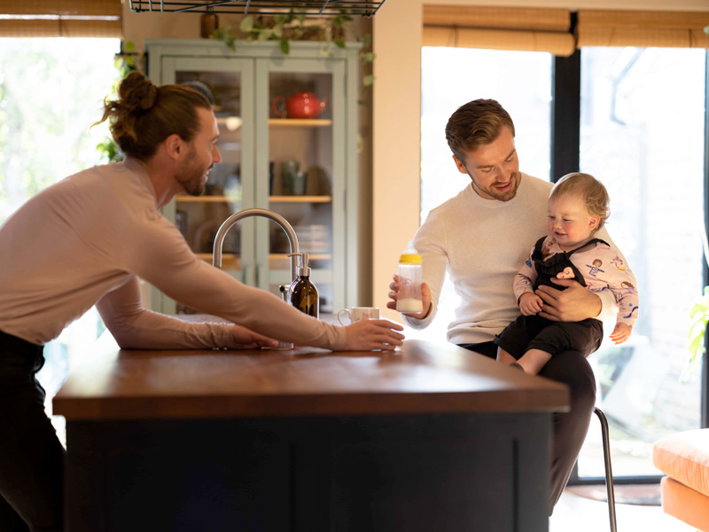 two dads in the kitchen with their baby