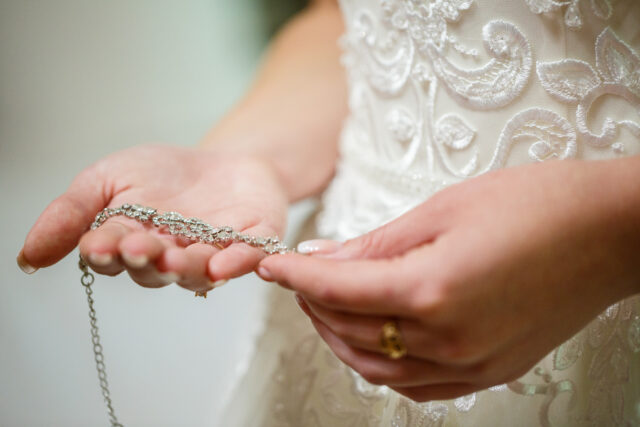 bride puts on wedding jewelry on the wedding day