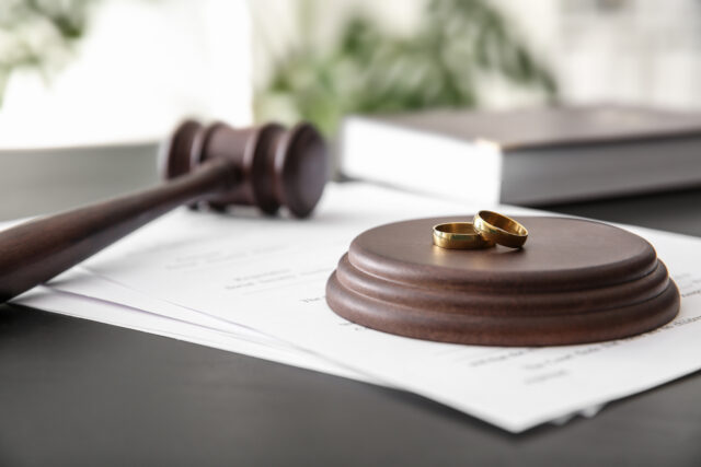 Rings with decree of divorce and judge gavel on table
